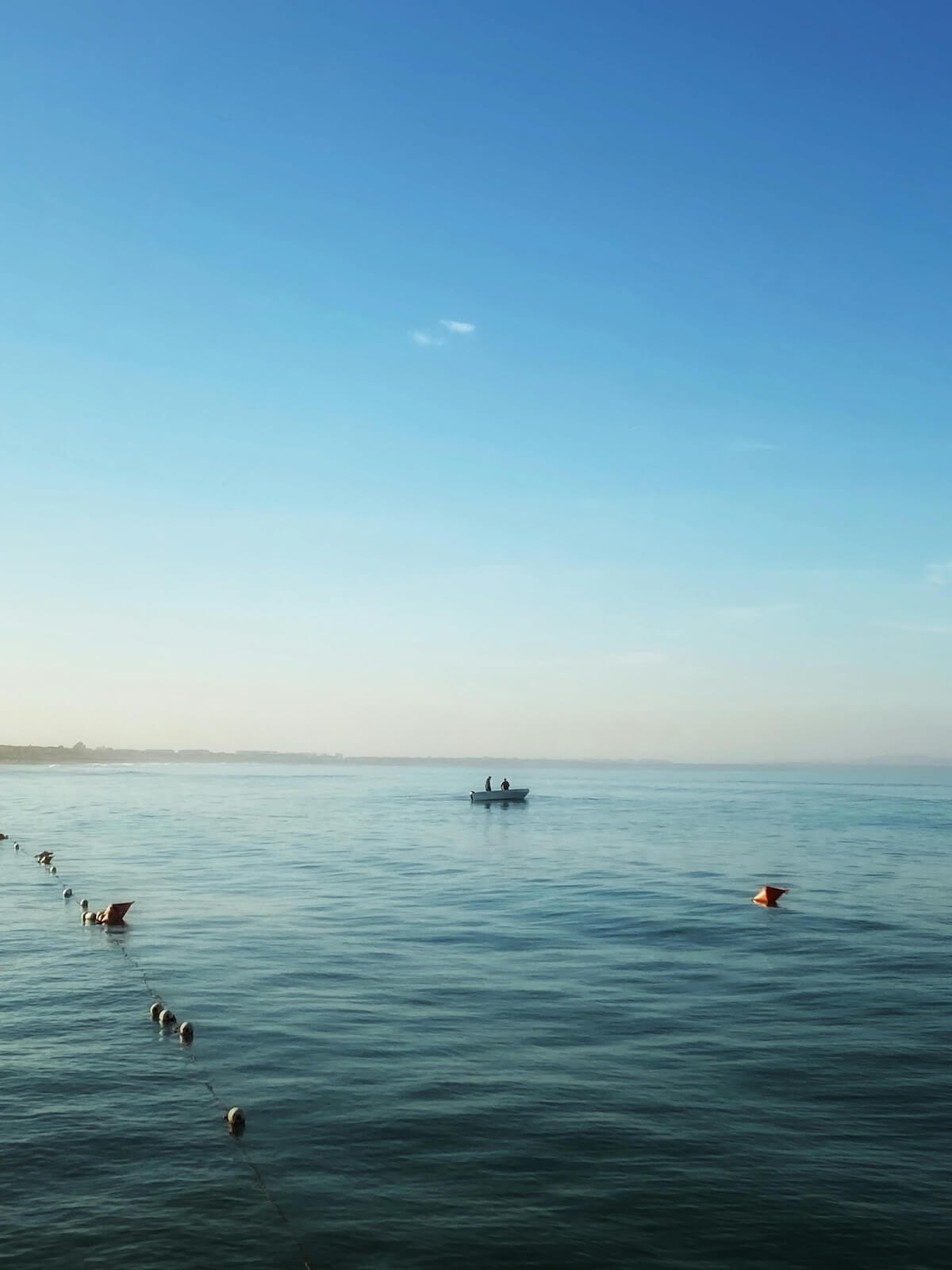 Tranquil morning at Durres Beach, Albania with boat on calm Adriatic waters