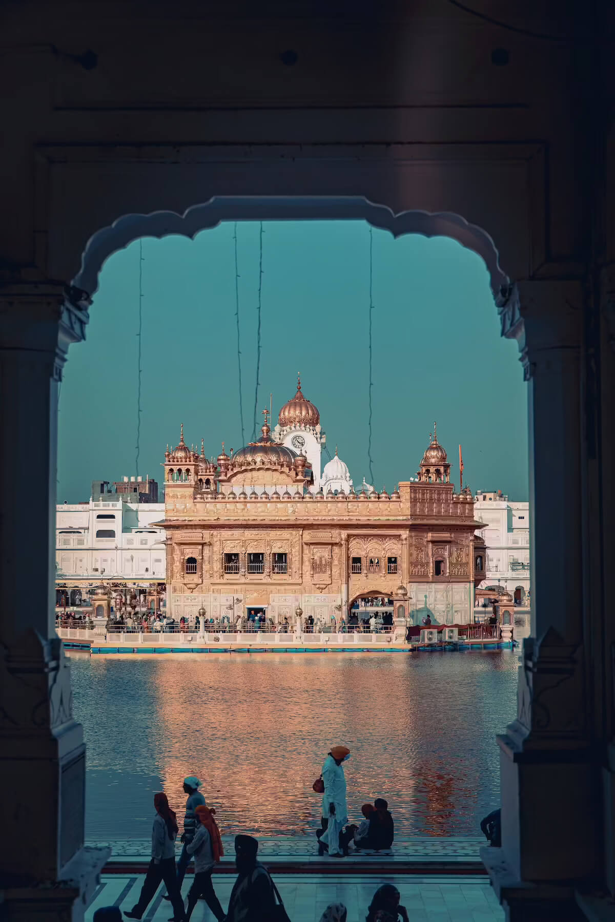 The Golden Temple framed by a marble archway and mirrored in the sarovar at dusk