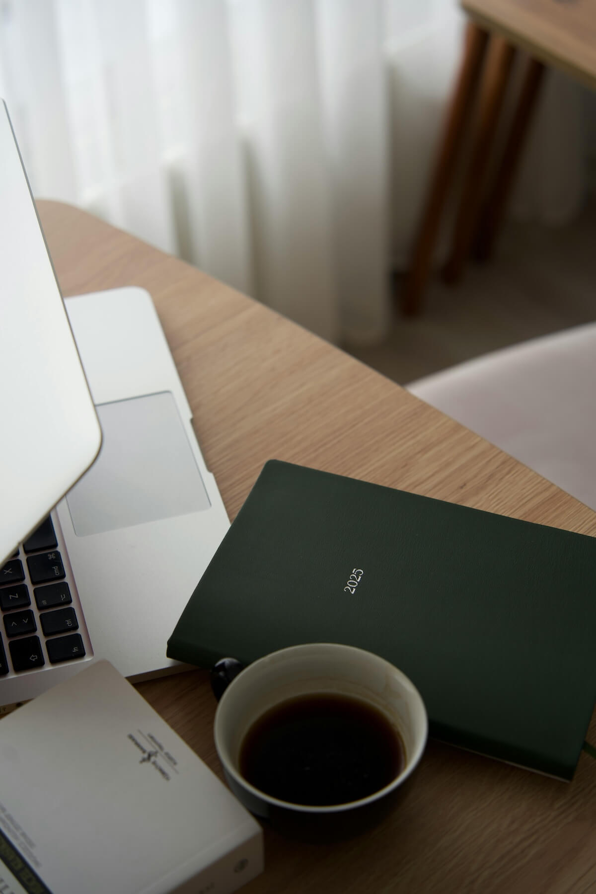 Minimalist workspace with open laptop, coffee cup and notebook on wooden desk