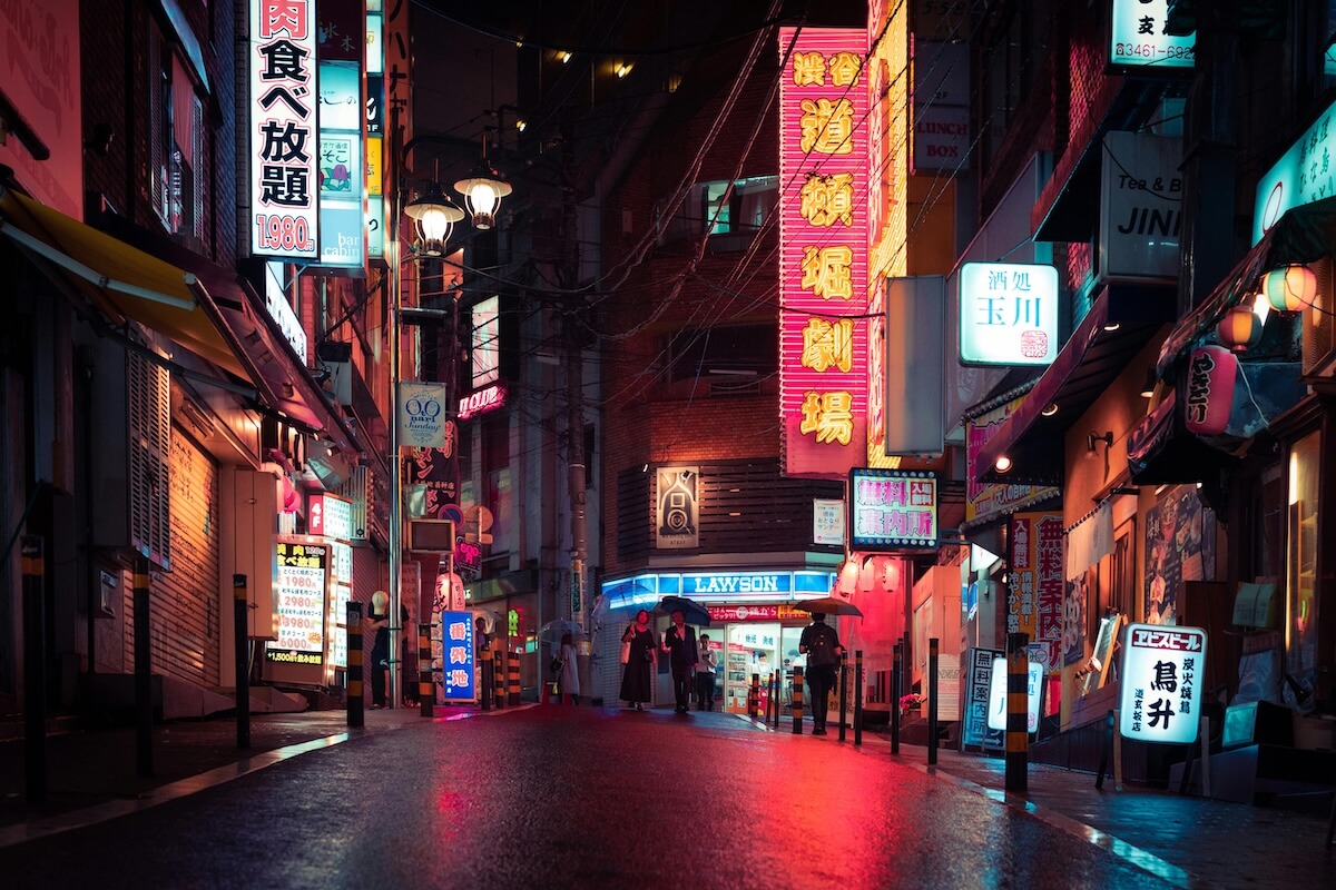 Neon-lit Tokyo street at night with crowds and illuminated restaurant signs