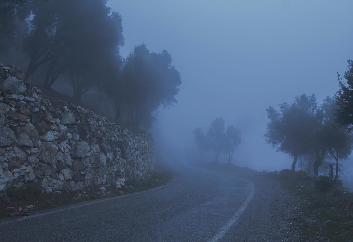 Misty mountain road winding through fog and rocky cliffs