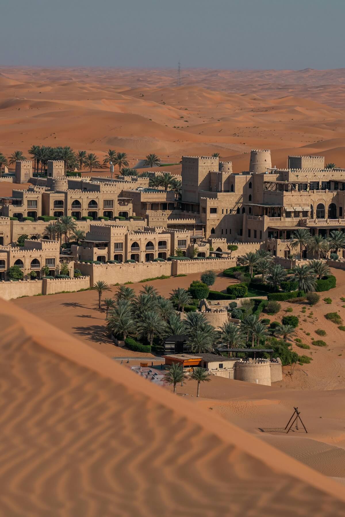 Aerial view of a castle surrounded by palm trees in the Arabian desert