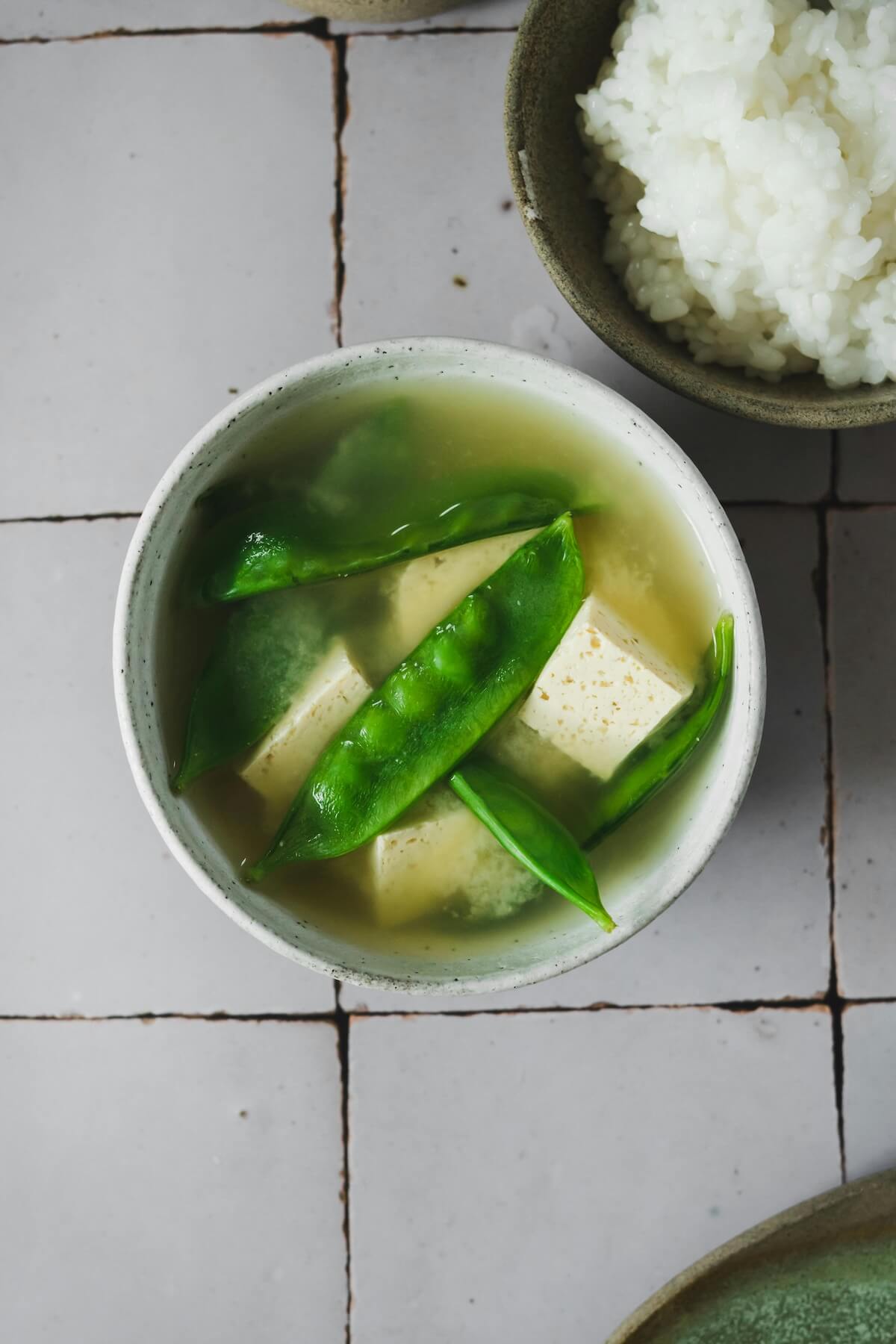 Traditional miso soup with tofu served alongside rice in ceramic bowls