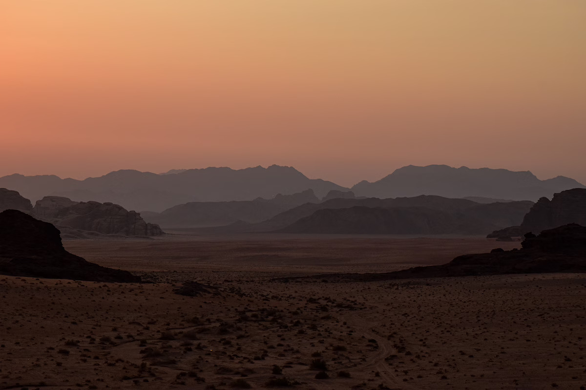 Silhouetted mountain ranges across the Wadi Rum desert at twilight in Jordan