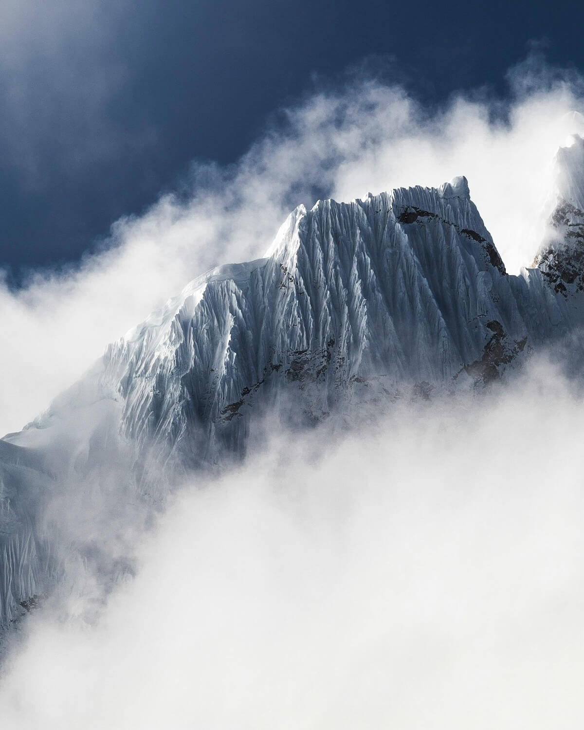 Snow-capped mountain peak rising through misty clouds