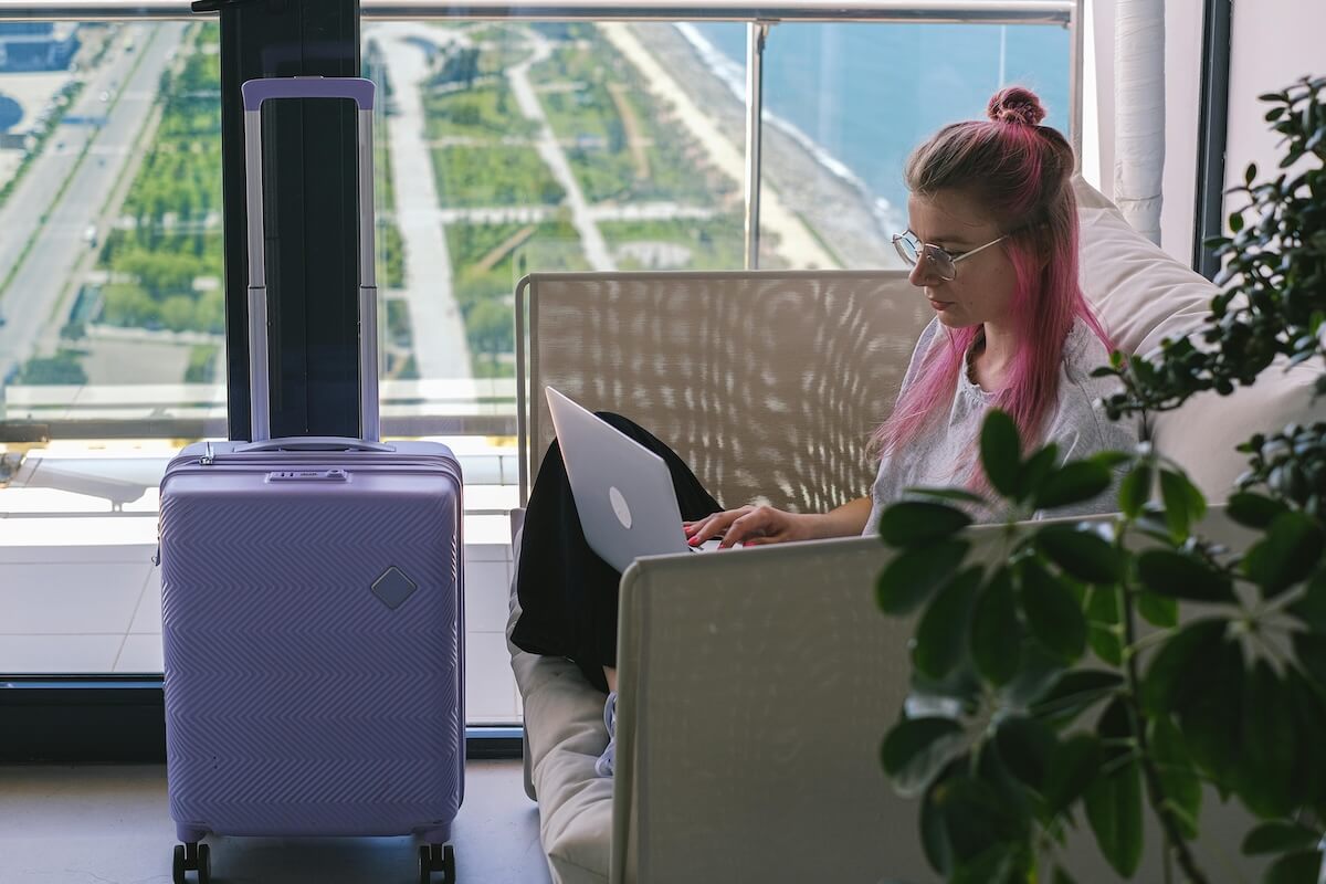 Digital nomad woman working on laptop in hotel room with scenic view
