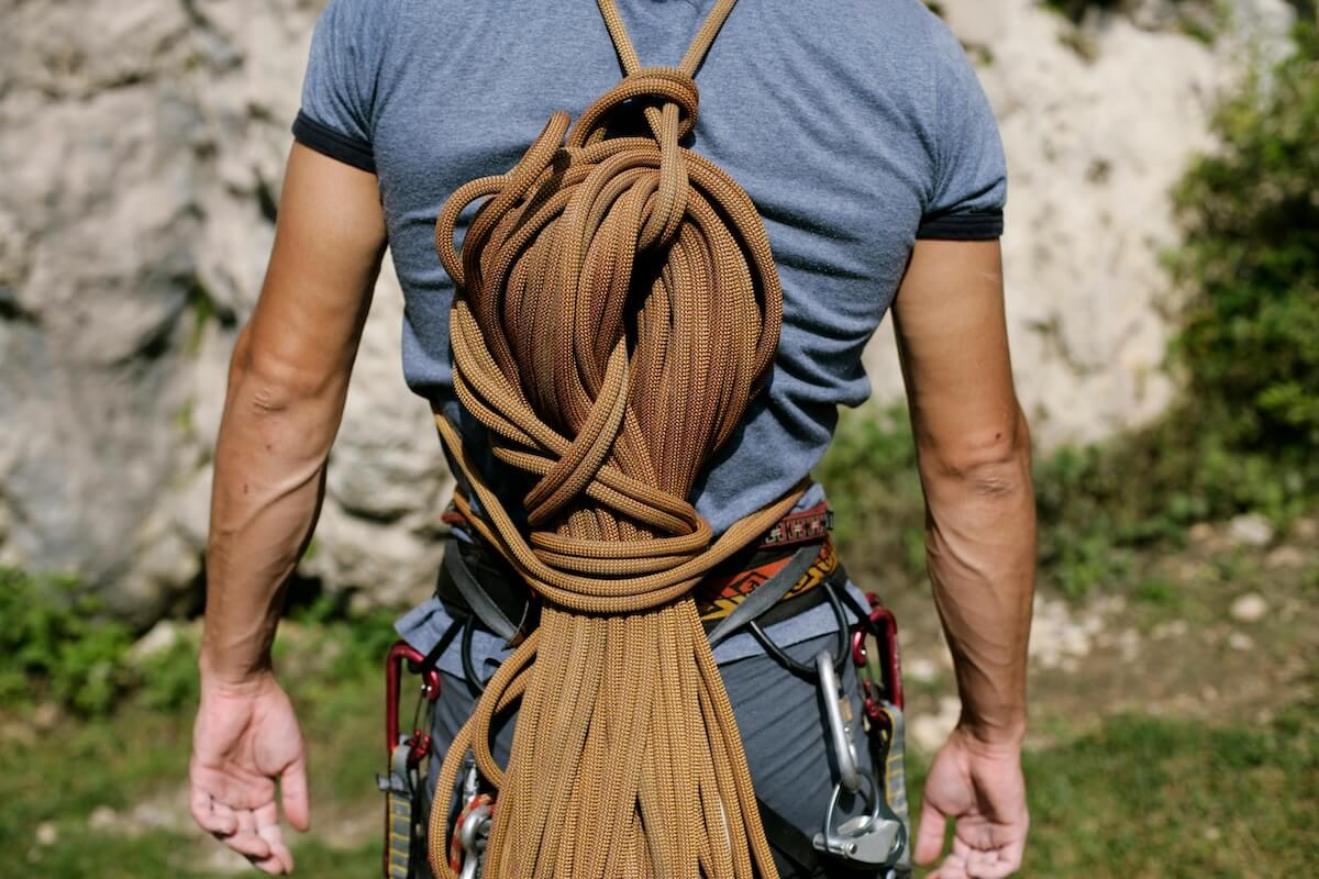 Mountain climber with harness carabiners and coiled rope