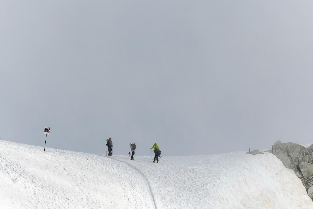 Three climbers ascending a snowy mountain peak