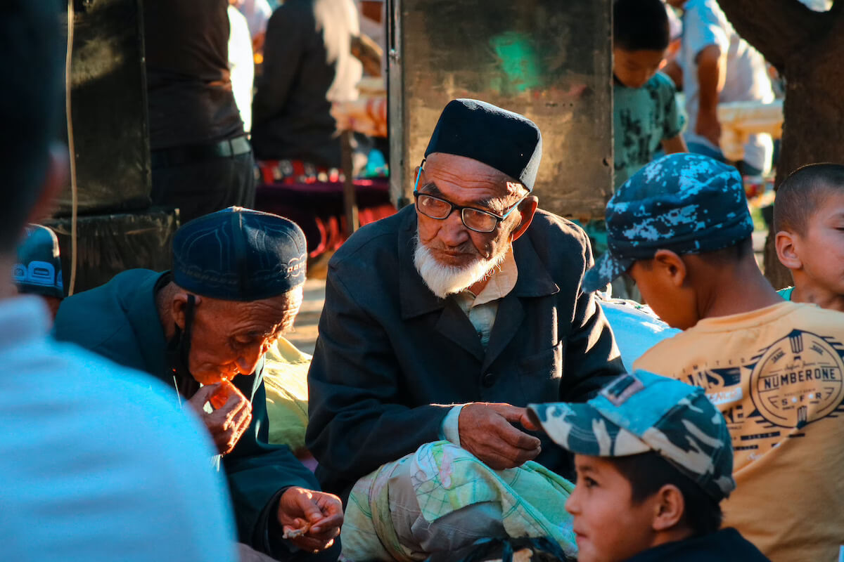 Older men and children sitting together at an outdoor market in Uzbekistan