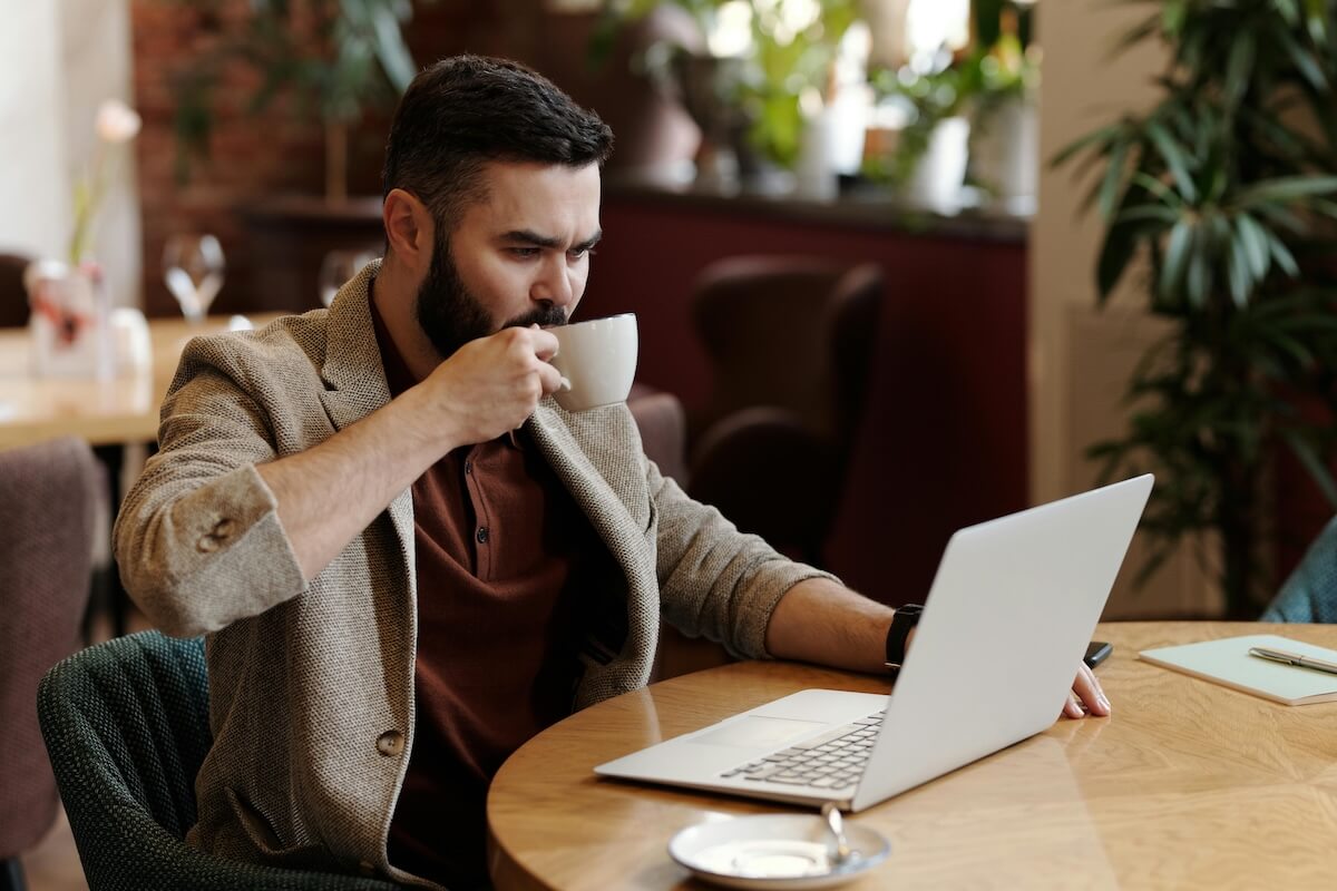 Man focused on laptop work in a comfortable cafe setting with coffee