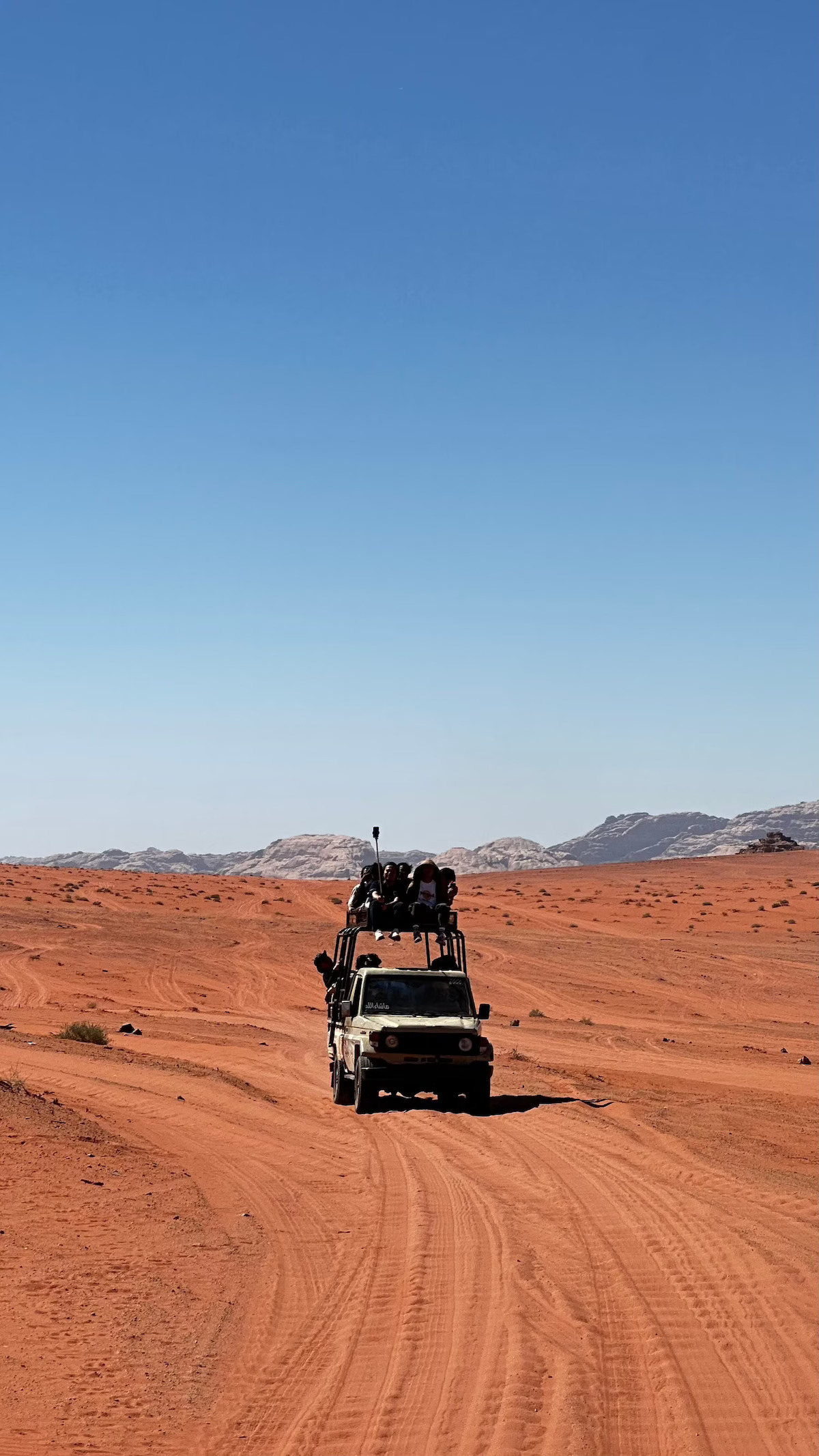 A 4x4 jeep carrying visitors across the red sand and sandstone formations of Wadi Rum, Jordan