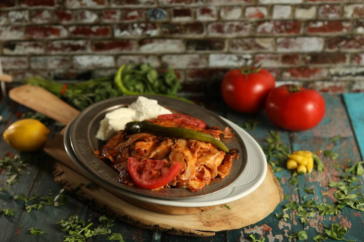 Iskender kebab served on a plate with tomatoes and peppers, a classic Turkish dish