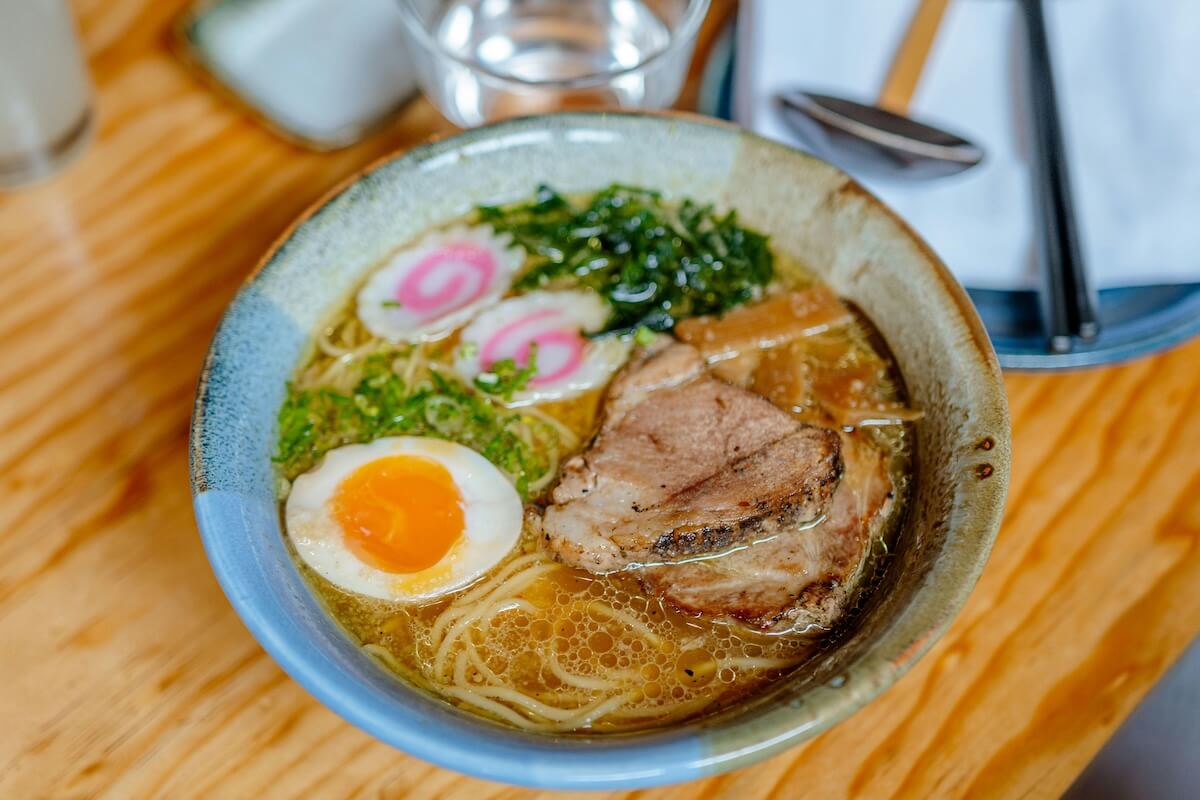 Savory bowl of Japanese ramen topped with pork, egg, and fresh garnishes