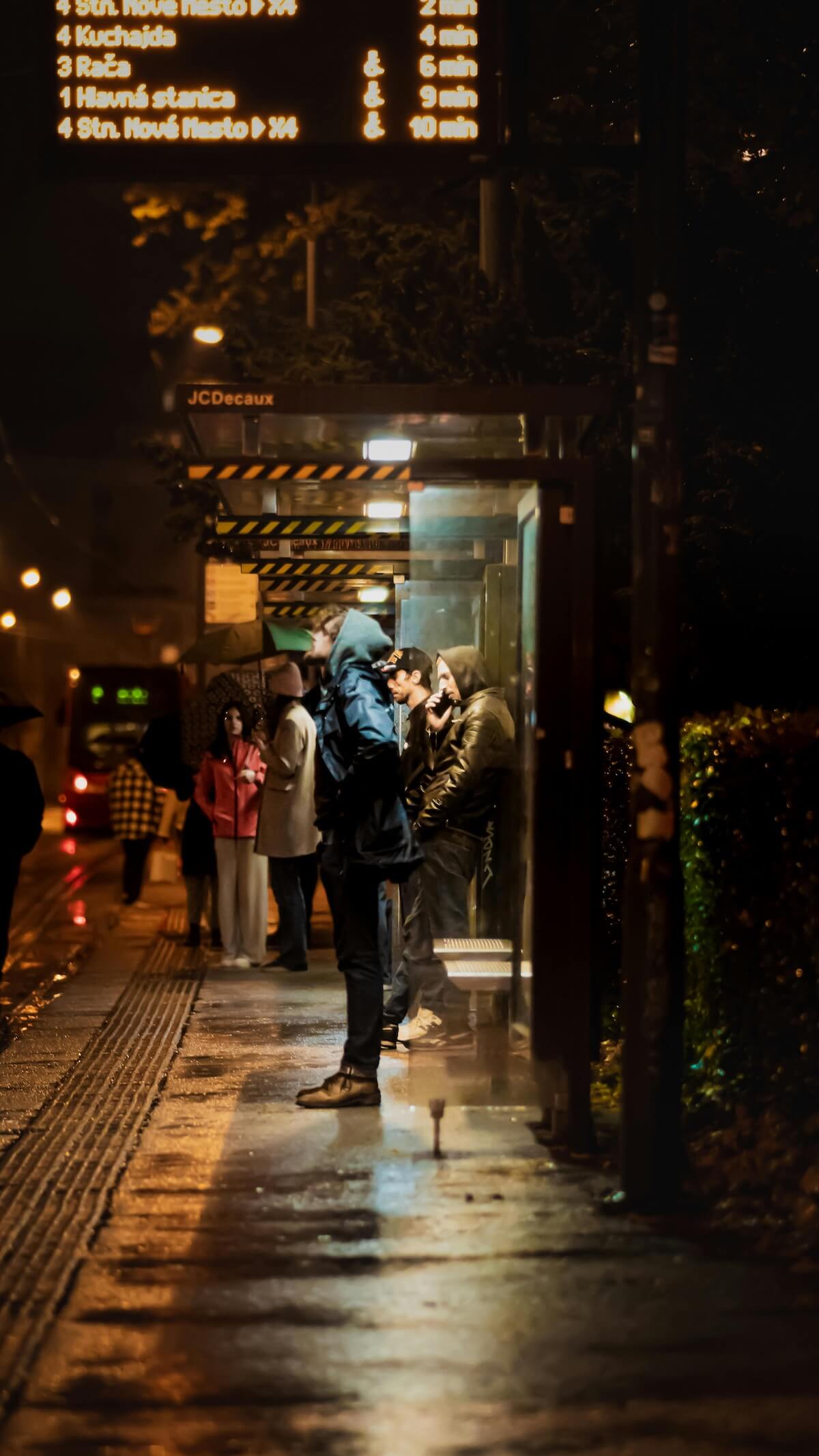 Group of passengers waiting at bus stop at night