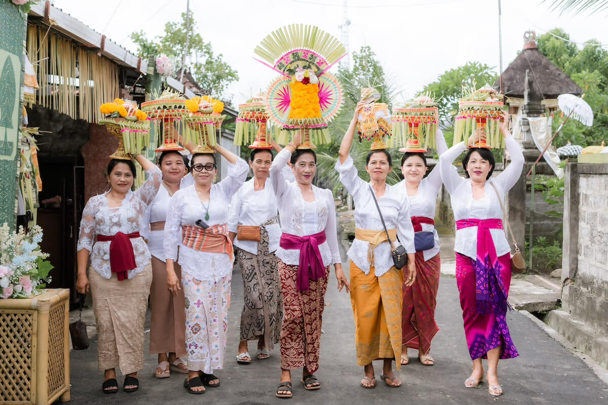Balinese women in traditional dress carrying ceremonial offerings on their heads during a village procession