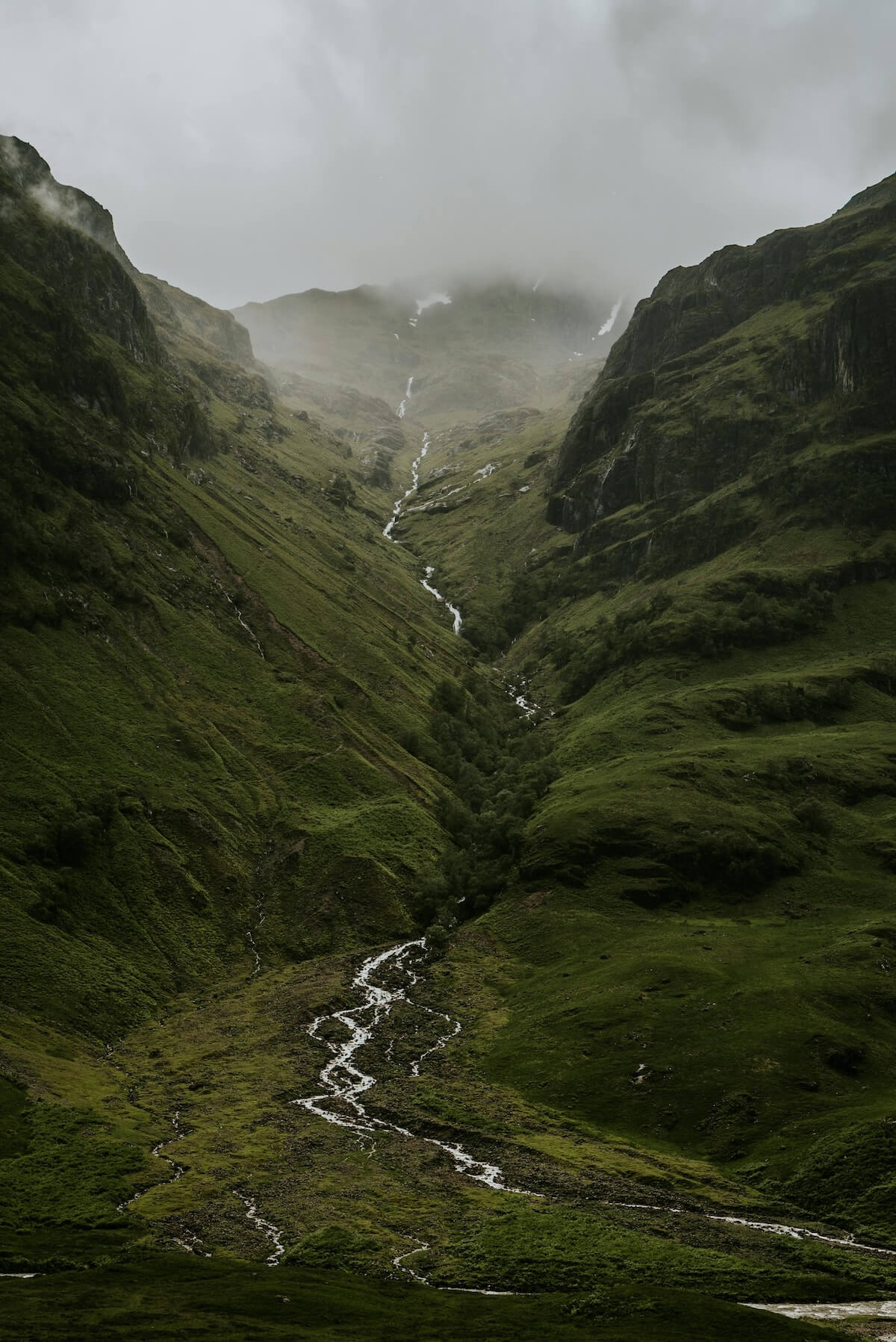 Misty Highland valley in Scotland with flowing river through green mountains