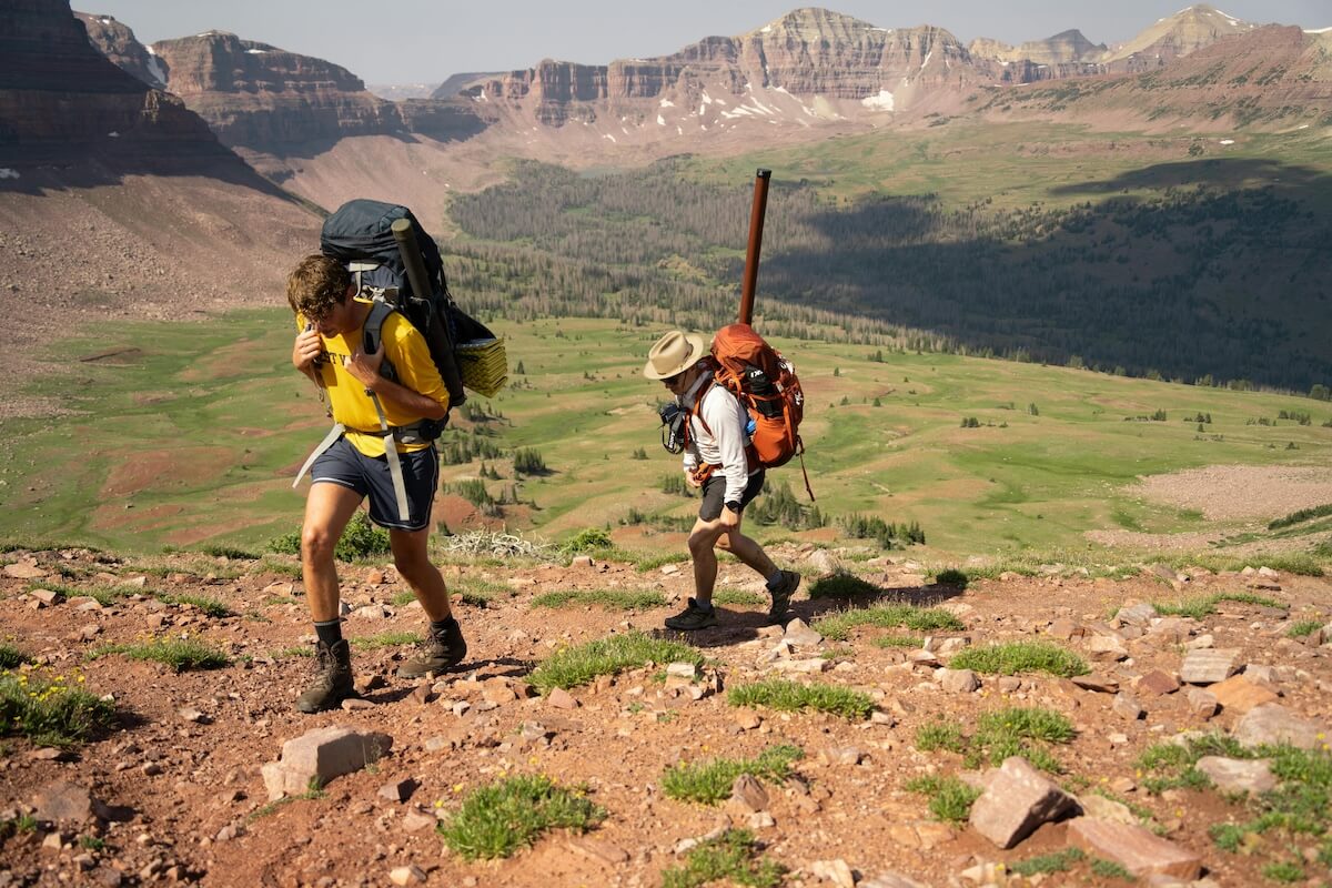 Hikers with backpacks ascending mountain trail