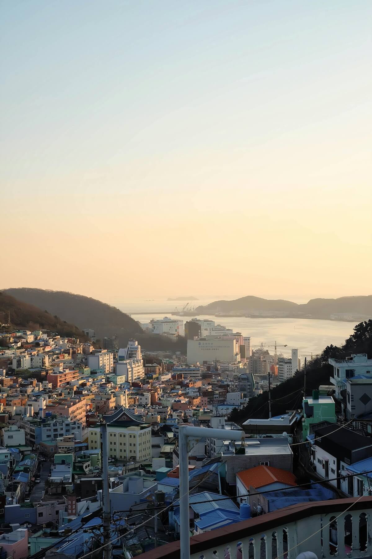 Sunset over Busan's coastal cityscape with mountains in background