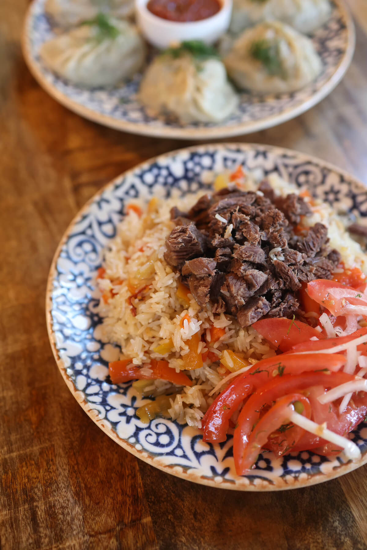 A plate of Uzbek plov with beef and dumplings served on a decorated blue ceramic dish