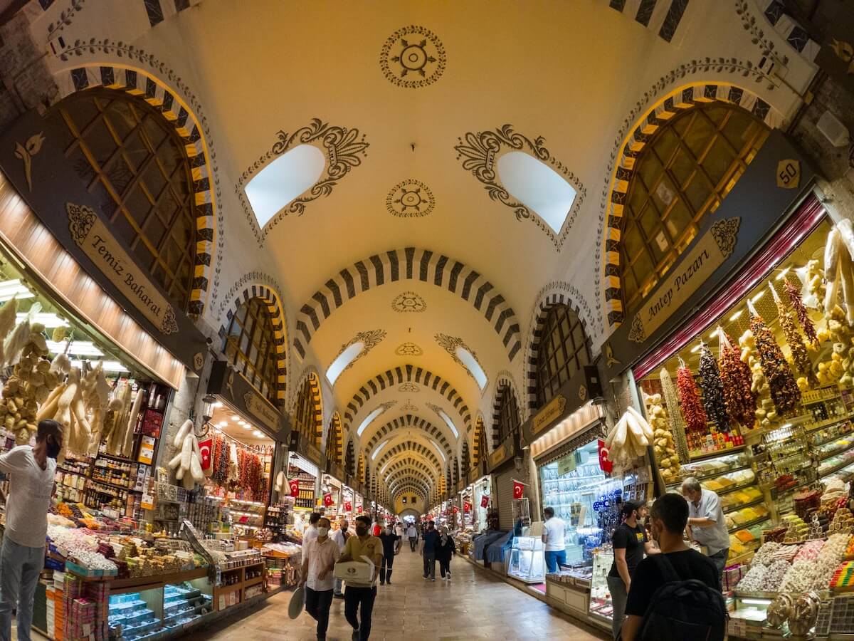 People shopping at a traditional spice bazaar with arched ceilings and vibrant stalls