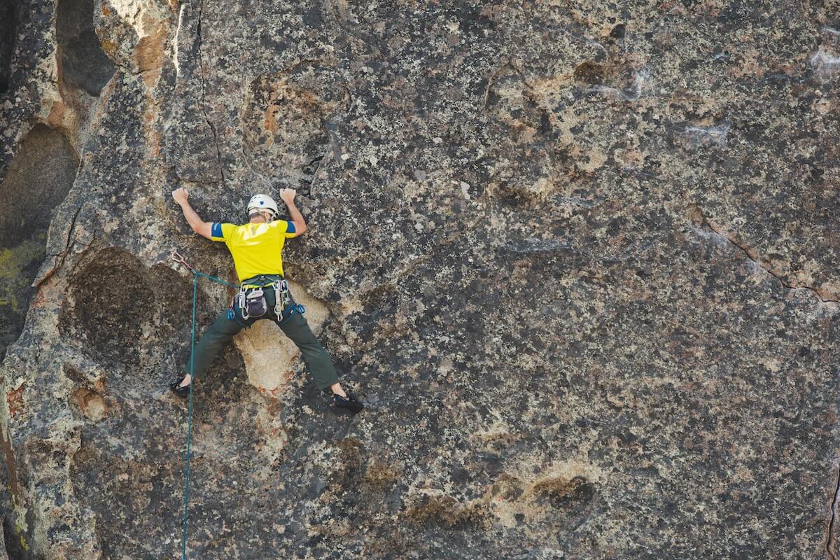 Man rock climbing on outdoor cliff face with rope