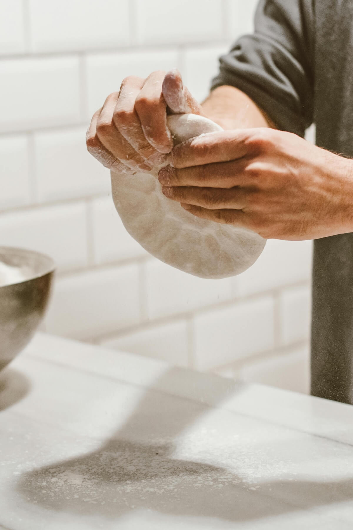 Hands kneading dough on marble surface, representing traditional food preparation