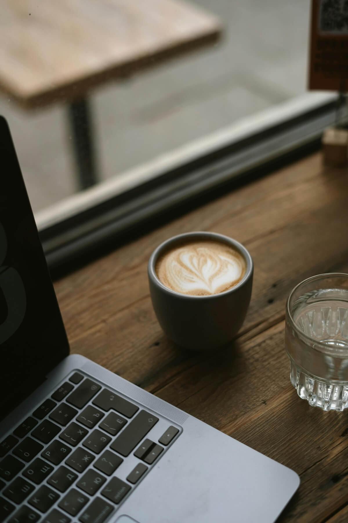 Laptop and coffee on wooden table in cafe setting