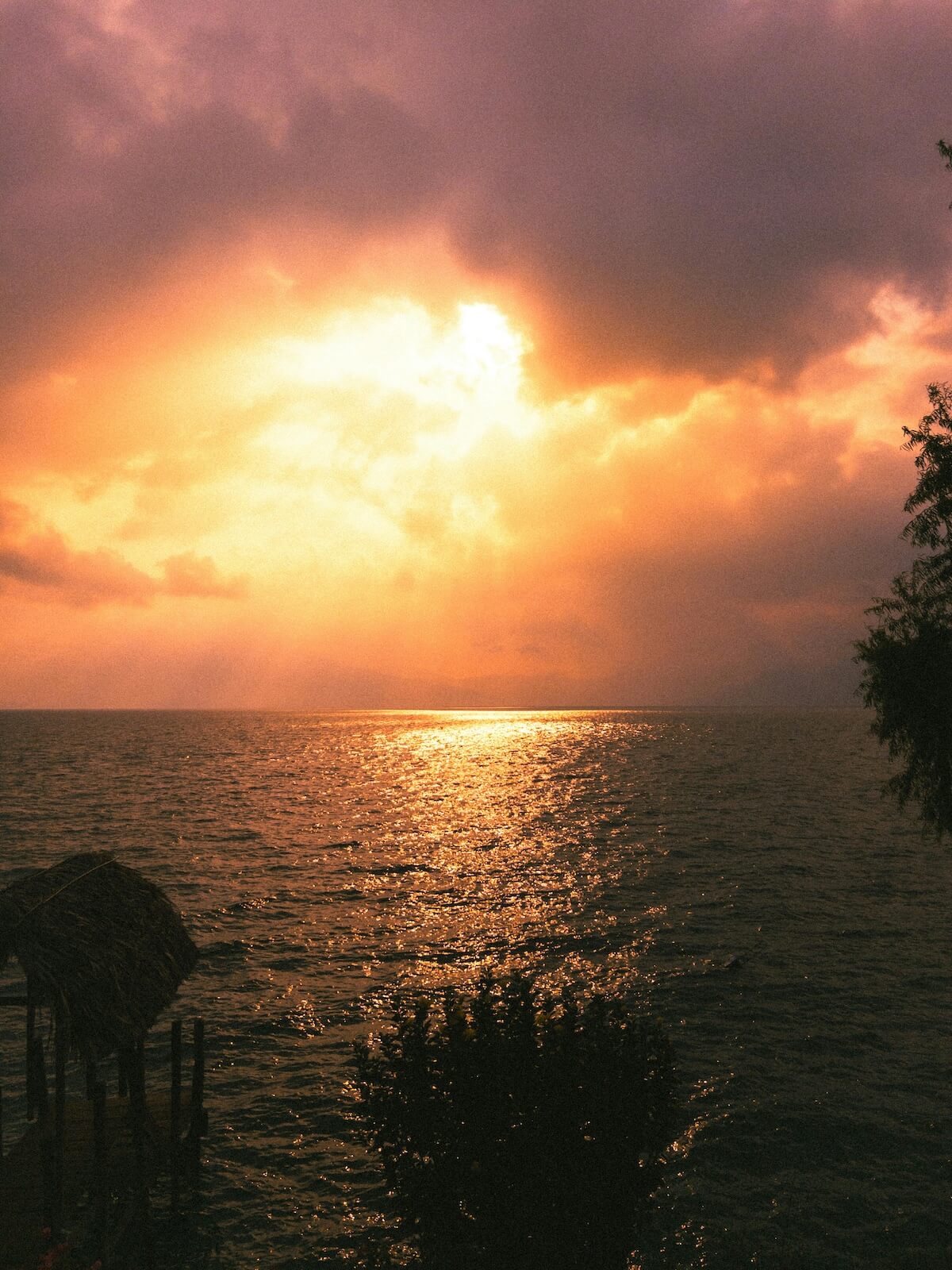 Sunset over Lake Atitlán with golden light reflecting on water and volcanic silhouettes