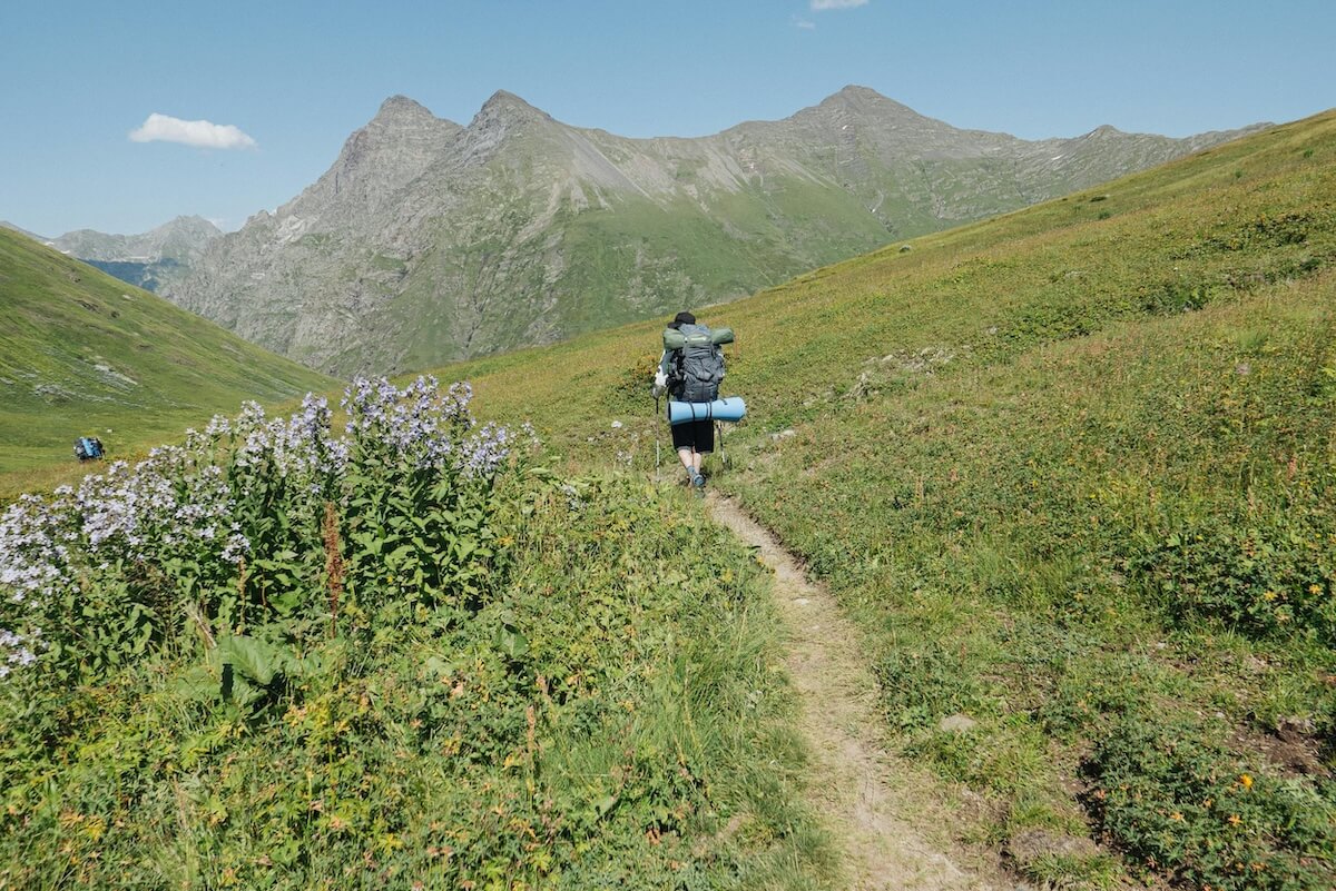 Hiker with backpack on forested mountain trail