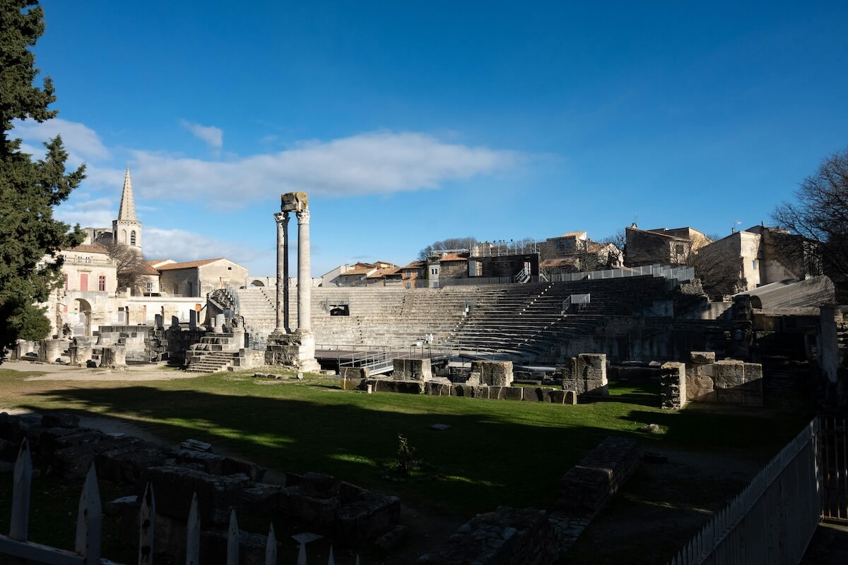 Ancient Roman amphitheater with stone arches and rows of seats under blue sky