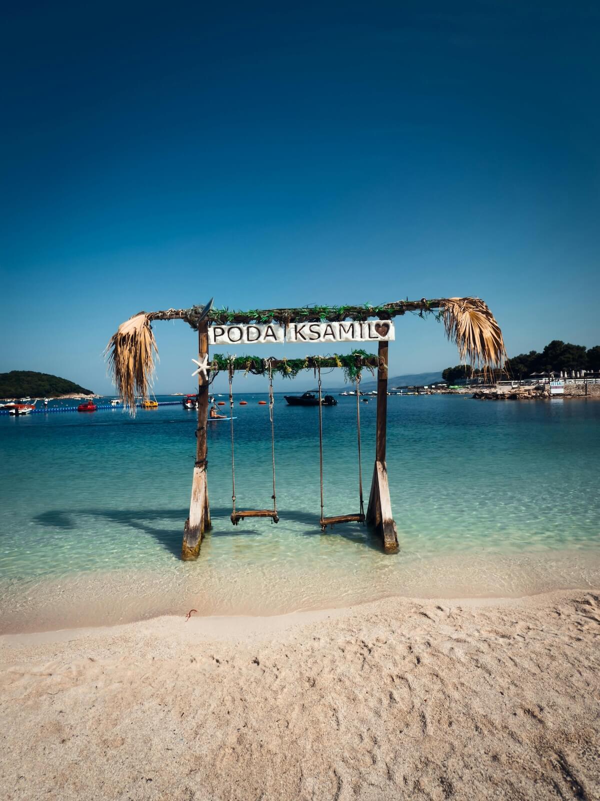 Beach swing overlooking crystal clear turquoise water on Albanian Riviera coastline